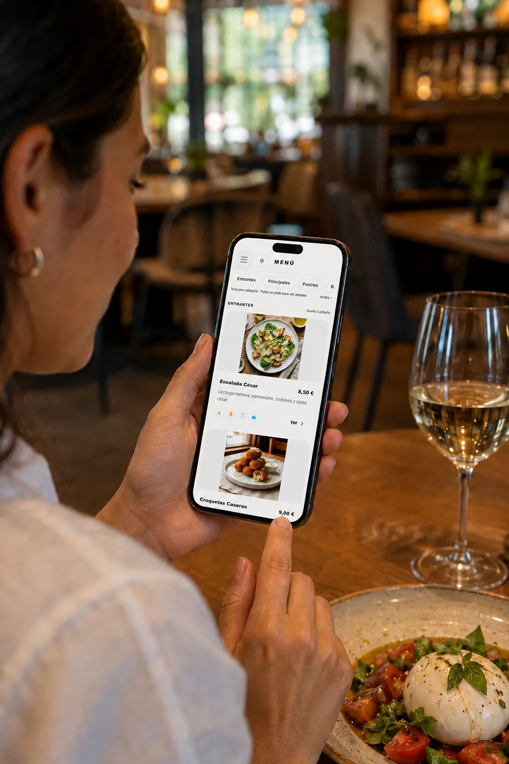 Una clienta consulta la carta digital en su móvil mientras está sentada a la mesa de un restaurante